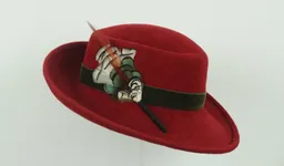 Green velvet ribbon and feather trim accent this poppy red velour with upturned brim